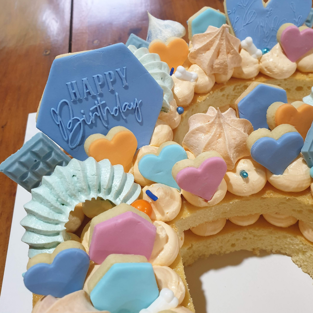 Close up of Bluey themed cake showing a blue wreath shaped meringue cake topper made using our wreath icing nozzle.