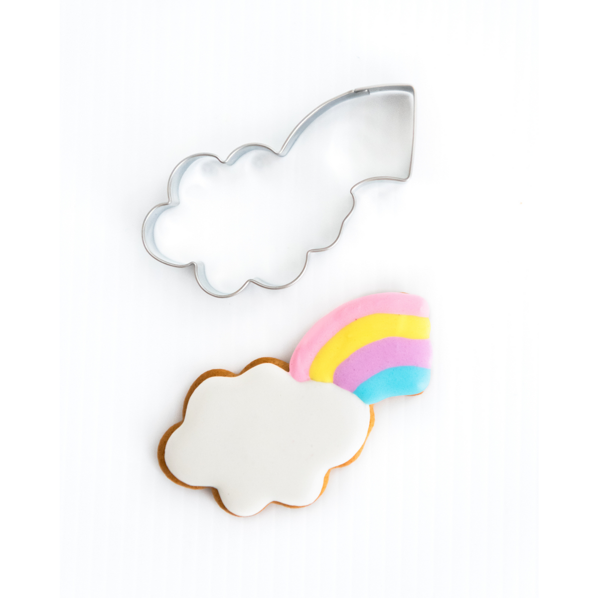 Rainbow coming out of cloud cookie cutter with cookie decorated with royal icing